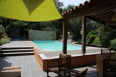 a pool with an umbrella and chairs and a table at La Bergerie - Les Sittelles in Pinarellu