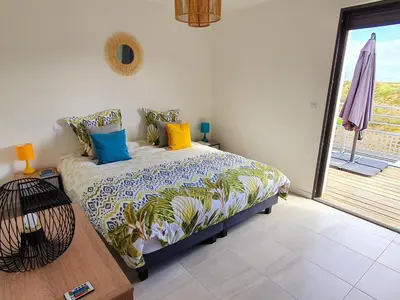 a bedroom with a bed with colorful pillows on it at T2 Yucca LCP - Beautiful 48 m2 2-room, 17 m2 terrace, new, air conditioning in Grosseto-Prugna