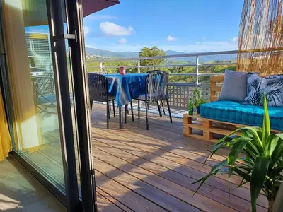 a deck with a table and chairs and a blue couch at T2 Yucca LCP - Beautiful 48 m2 2-room, 17 m2 terrace, new, air conditioning in Grosseto-Prugna