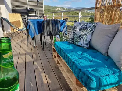 a blue couch sitting on a deck with a table at T2 Yucca LCP - Beautiful 48 m2 2-room, 17 m2 terrace, new, air conditioning in Grosseto-Prugna