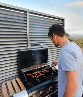 a man is cooking food on a grill at T2 Yucca LCP - Beautiful 48 m2 2-room, 17 m2 terrace, new, air conditioning in Grosseto-Prugna