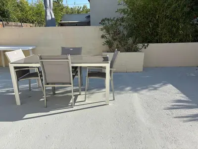 a white table and chairs sitting on a patio at T2 climatisé avec piscine in Prunelli-di-Fiumorbo