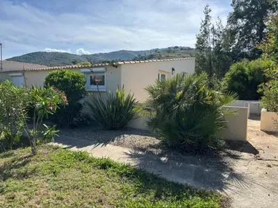 a white house with plants in front of it at T2 climatisé avec piscine in Prunelli-di-Fiumorbo
