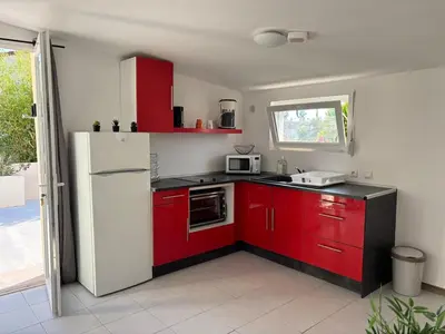 a kitchen with red cabinets and a white refrigerator at T2 climatisé avec piscine in Prunelli-di-Fiumorbo