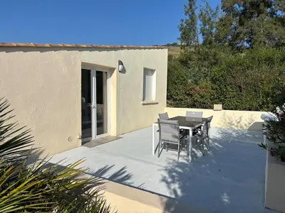a patio with a table and chairs next to a building at T2 climatisé avec piscine in Prunelli-di-Fiumorbo