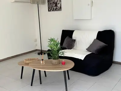 a living room with a black couch and a table at T2 climatisé avec piscine in Prunelli-di-Fiumorbo