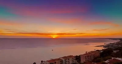 a sunset over a beach with buildings and the ocean at VUE MER EXCEPTIONNELLE !! Bien calme et lumineux sur la prestigieuse route des Sanguinaires à Ajaccio in Ajaccio