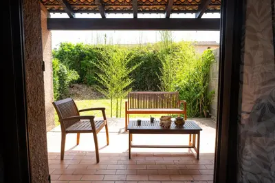 a patio with two chairs and a table and a bench at maison climatisée fibrée 2 chambres à 9 min à pieds d'une grande plage in Venzolasca