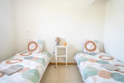 two twin beds in a room with a table at maison climatisée fibrée 2 chambres à 9 min à pieds d'une grande plage in Venzolasca