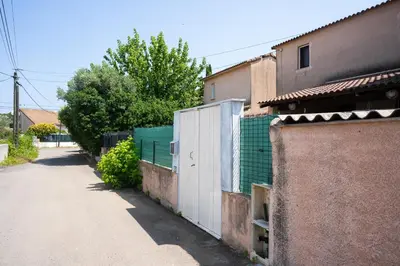 a building with a fence next to a street at maison climatisée fibrée 2 chambres à 9 min à pieds d'une grande plage in Venzolasca