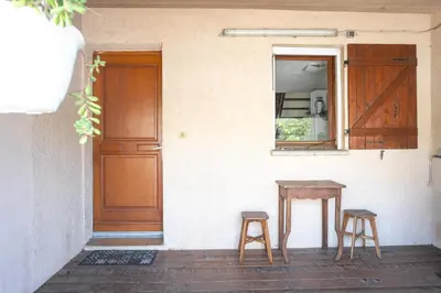 a table and two stools in front of a door at maison climatisée fibrée 2 chambres à 9 min à pieds d'une grande plage in Venzolasca