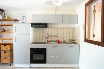 a kitchen with white cabinets and a white refrigerator at maison climatisée fibrée 2 chambres à 9 min à pieds d'une grande plage in Venzolasca