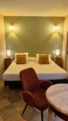 a bedroom with a bed and a chair and a table at Colomba Hôtel Centre-Ville Historique in Bonifacio