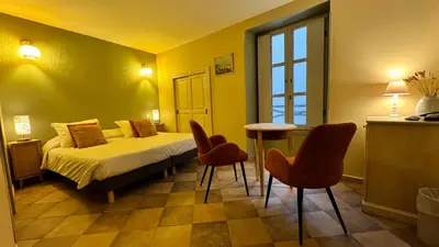 a bedroom with a bed with chairs and a table at Colomba Hôtel Centre-Ville Historique in Bonifacio