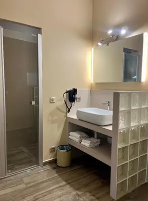 a bathroom with a sink and a mirror and a shower at Colomba Hôtel Centre-Ville Historique in Bonifacio