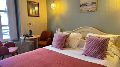 a bedroom with a bed with pink and white pillows at Colomba Hôtel Centre-Ville Historique in Bonifacio