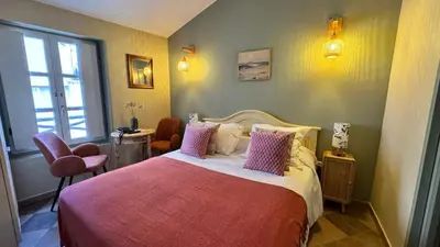 a bedroom with a large bed with pink pillows at Colomba Hôtel Centre-Ville Historique in Bonifacio