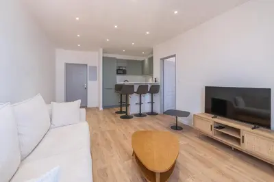 a living room with a white couch and a television at T2 40m2 climatisé centre ville FESCH in Ajaccio