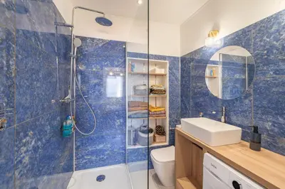 a blue tiled bathroom with a shower and a sink at T2 40m2 climatisé centre ville FESCH in Ajaccio