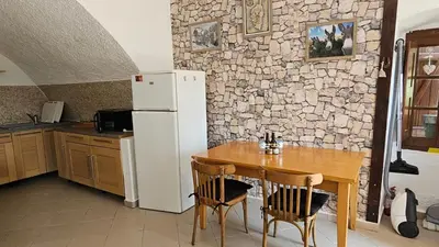 a kitchen with a table and a white refrigerator at Location de charme au coeur de la Corse - Piscine privative - calme - nature in San-Lorenzo
