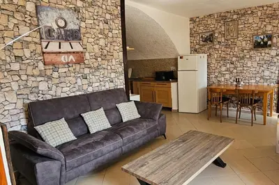 a living room with a couch and a stone wall at Location de charme au coeur de la Corse - Piscine privative - calme - nature in San-Lorenzo