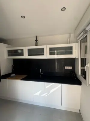 a kitchen with white cabinets and a black counter top at Villa Domaine U Murtonu in Porto-Vecchio
