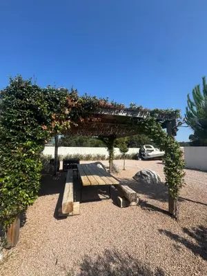 a picnic bench under a pergola with flowers at Villa Domaine U Murtonu in Porto-Vecchio