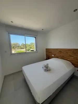 a bedroom with a large white bed with a window at Villa Domaine U Murtonu in Porto-Vecchio