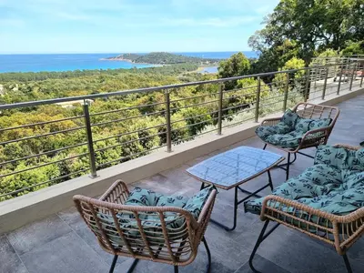 a balcony with chairs and a table and the ocean at Villa Pinarello vue panoramique mer piscine privée chauffée, plage à 900m in Zonza