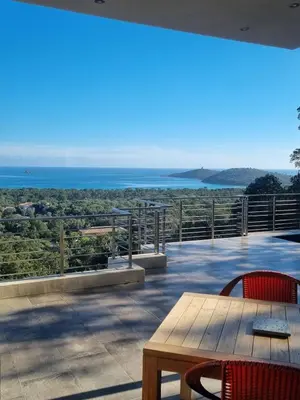 a patio with a table and chairs and the ocean at Villa Pinarello vue panoramique mer piscine privée chauffée, plage à 900m in Zonza