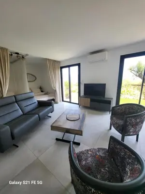 a living room with a couch and a table and chairs at Bas de villa aux portes d'Ajaccio in Alata