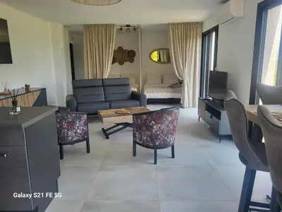 a living room with a couch and a table and chairs at Bas de villa aux portes d'Ajaccio in Alata