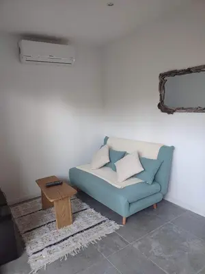 a living room with a blue couch and a table at Charmante maisonette in Porto-Vecchio