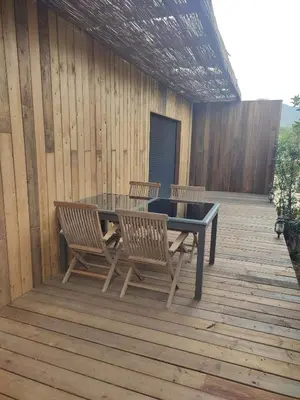 a patio with a table and chairs on a wooden deck at Charmante maisonette in Porto-Vecchio