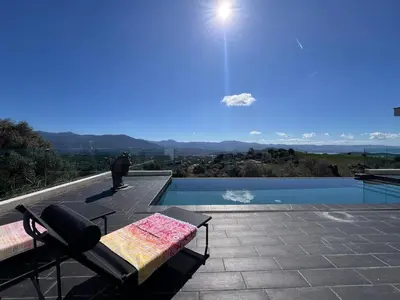 a patio with a table and a bench next to a pool at Haut de villa aux portes d'Ajaccio in Alata