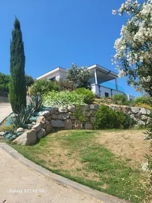 a house on a hill with a stone wall at Haut de villa aux portes d'Ajaccio in Alata