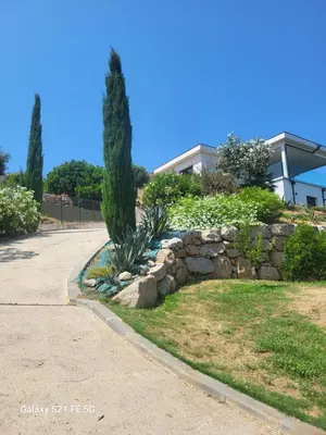 a stone retaining wall with a tree and a building at Haut de villa aux portes d'Ajaccio in Alata