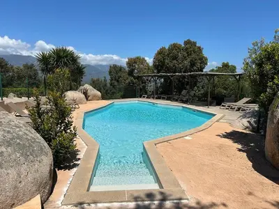 a swimming pool with blue water in a yard at Villa Roccapina - Porto-Vecchio in Sotta