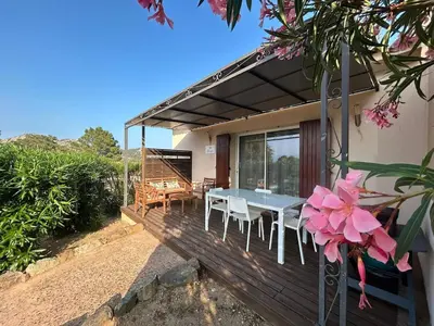 a house with a table and chairs on a deck at Villa Roccapina - Porto-Vecchio in Sotta