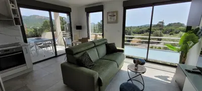 a living room with a green couch and large windows at Dormir à Pinarello Corse du Sud 4 pers Vue Mer in Sainte-Lucie de Porto-Vecchio