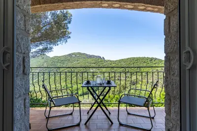 a patio with a table and chairs on a balcony at U Tadu - Maison de vacances en pierre avec vue et nature en Corse du Sud in Monacia-dʼAullène