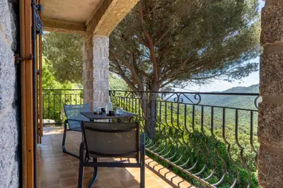 a patio with a table and chairs on a balcony at U Tadu - Maison de vacances en pierre avec vue et nature en Corse du Sud in Monacia-dʼAullène