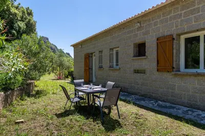 a table and chairs in front of a brick house at U Tadu - Maison de vacances en pierre avec vue et nature en Corse du Sud in Monacia-dʼAullène