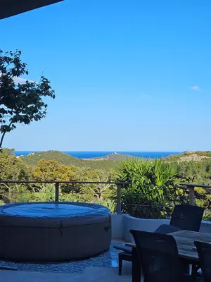 a hot tub on a patio with a table and chairs at Maison au coeur du maquis in Porto-Vecchio