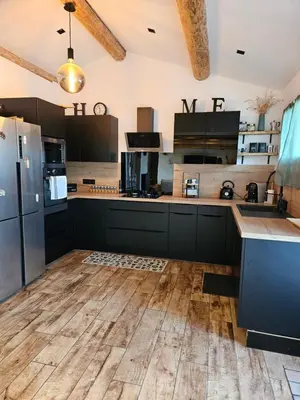 a kitchen with black cabinets and a wooden floor at Maison au coeur du maquis in Porto-Vecchio