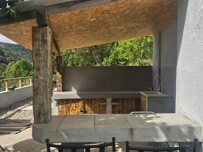 a kitchen with a sink and a table with chairs at Maison au coeur du maquis in Porto-Vecchio
