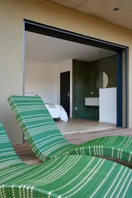 a green chair in a room with a bedroom at Les chambres Toussaint in Pianottoli-Caldarello