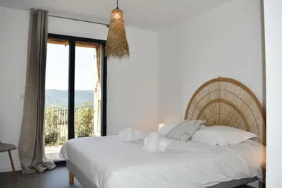 a bedroom with a white bed and a large window at Amandula Bergerie Sotta hyper cozy in Sotta