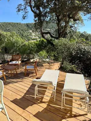 two chairs and tables on a wooden deck at CASA ANPÀ Maison Vue Mer in Lecci