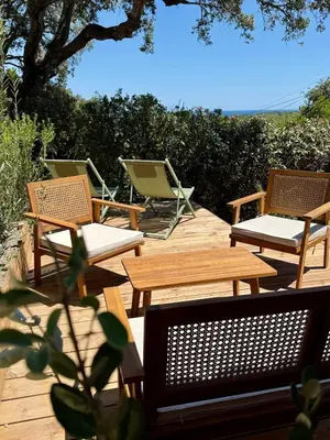 a group of chairs and tables on a wooden deck at CASA ANPÀ Maison Vue Mer in Lecci